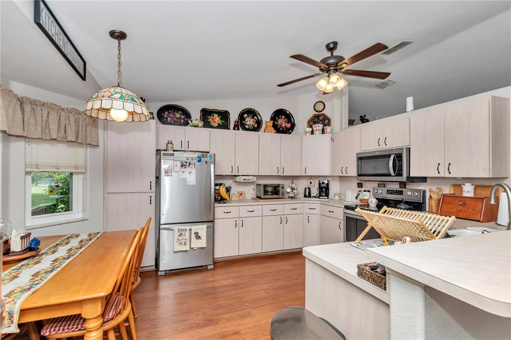10086 Southwest 62nd Ter Road Ocala, FL 34476 - Photo 10 of 40 a kitchen with a refrigerator a stove a sink dishwasher a dining table and chairs with wooden floor
