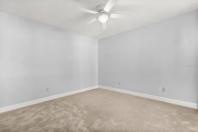 an empty room with a fan & a ceiling fan