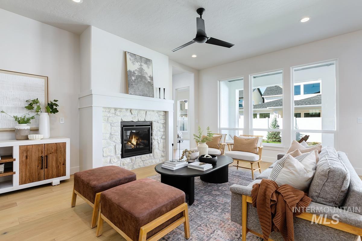 5817 South Gustav Avenue Meridian, ID 83642 - Photo 2 of 33 Living space featuring a stone-surround fireplace with a white mantel, light wood-finish flooring, recessed lighting, and a modern ceiling fan