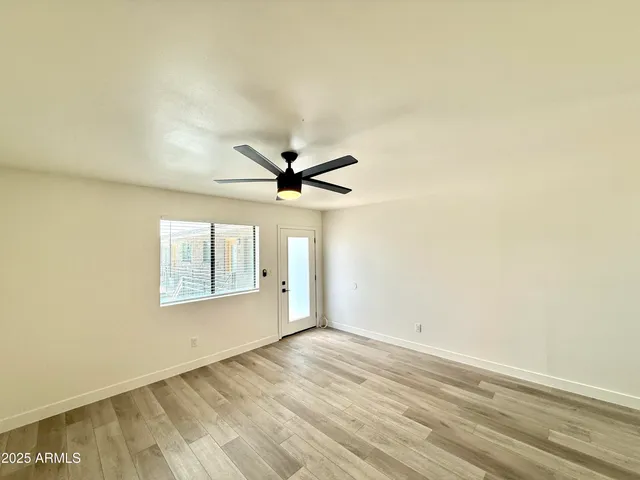 a view of empty room with wooden floor and fan
