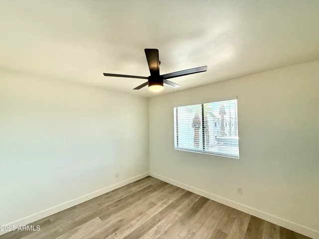an empty room with a window and ceiling fan