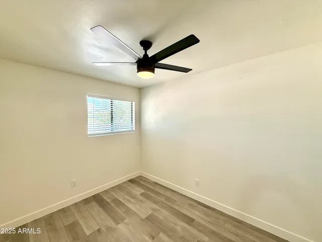 an empty room with a ceiling fan and wooden floor
