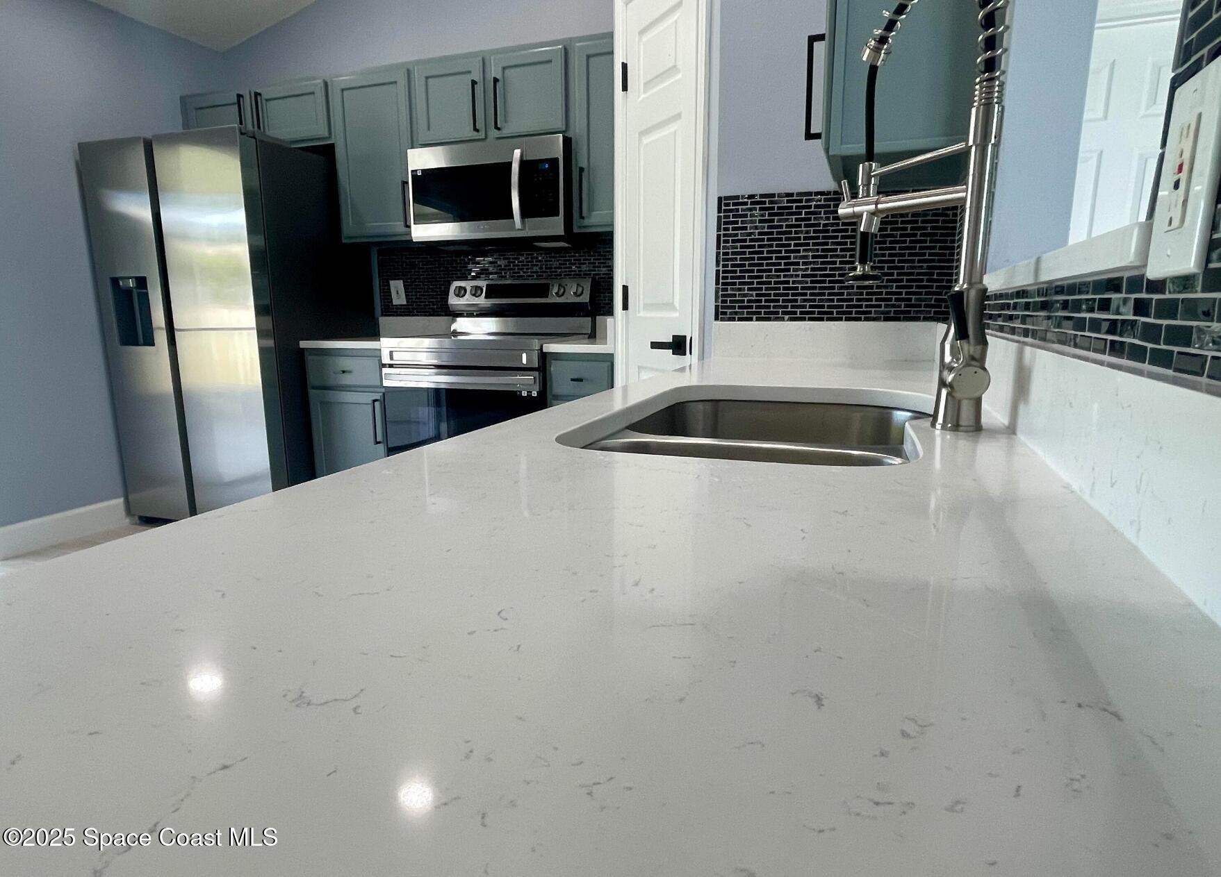2226 Redwood Circle Palm Bay, FL 32905 - Photo 12 of 27 a kitchen with stainless steel appliances a sink a stove top oven a refrigerator and cabinets