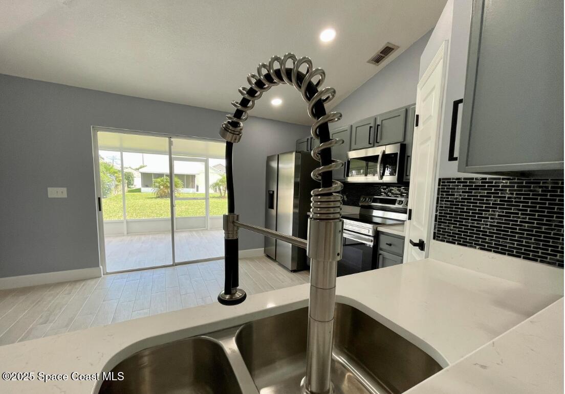 2226 Redwood Circle Palm Bay, FL 32905 - Photo 14 of 27 a kitchen with stainless steel appliances kitchen island granite countertop a sink a stove and refrigerator