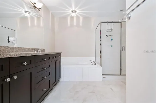 a bathroom with a granite countertop sink a mirror a bathtub and shower