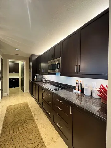 a large kitchen with granite countertop a sink and cabinets