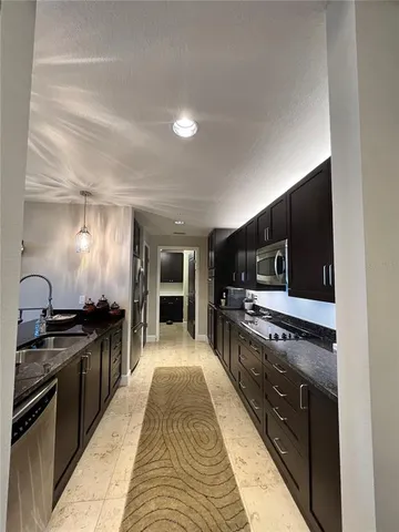 a kitchen with stainless steel appliances kitchen island granite countertop a stove top oven a sink dishwasher a dining table and chairs a stove with wooden floor