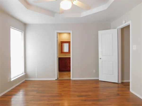 a view of an empty room with window and wooden floor