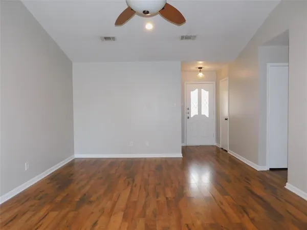 an empty room with wooden floor and windows