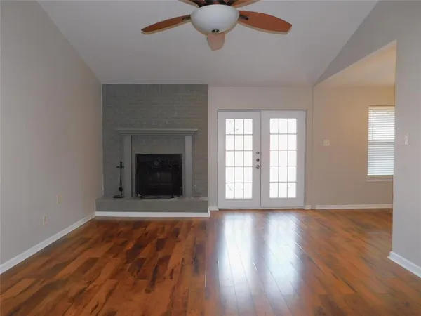 wooden floor fireplace and windows in an empty room