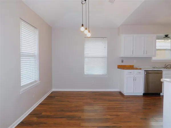 a kitchen with granite countertop white cabinets and wooden floor