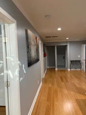 a view of a hallway with wooden floor and a bathroom