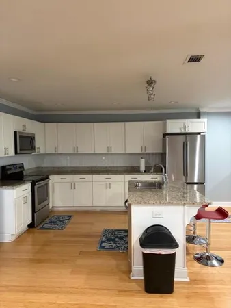 a kitchen with stainless steel appliances granite countertop a stove a sink a refrigerator and white cabinets