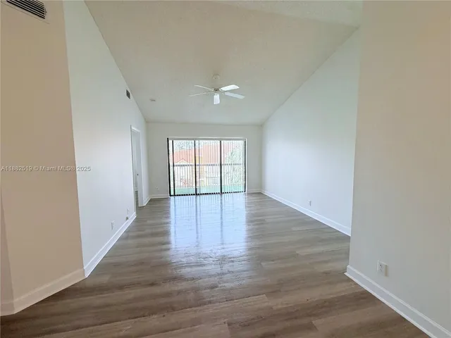 a view of an empty room with wooden floor and windows