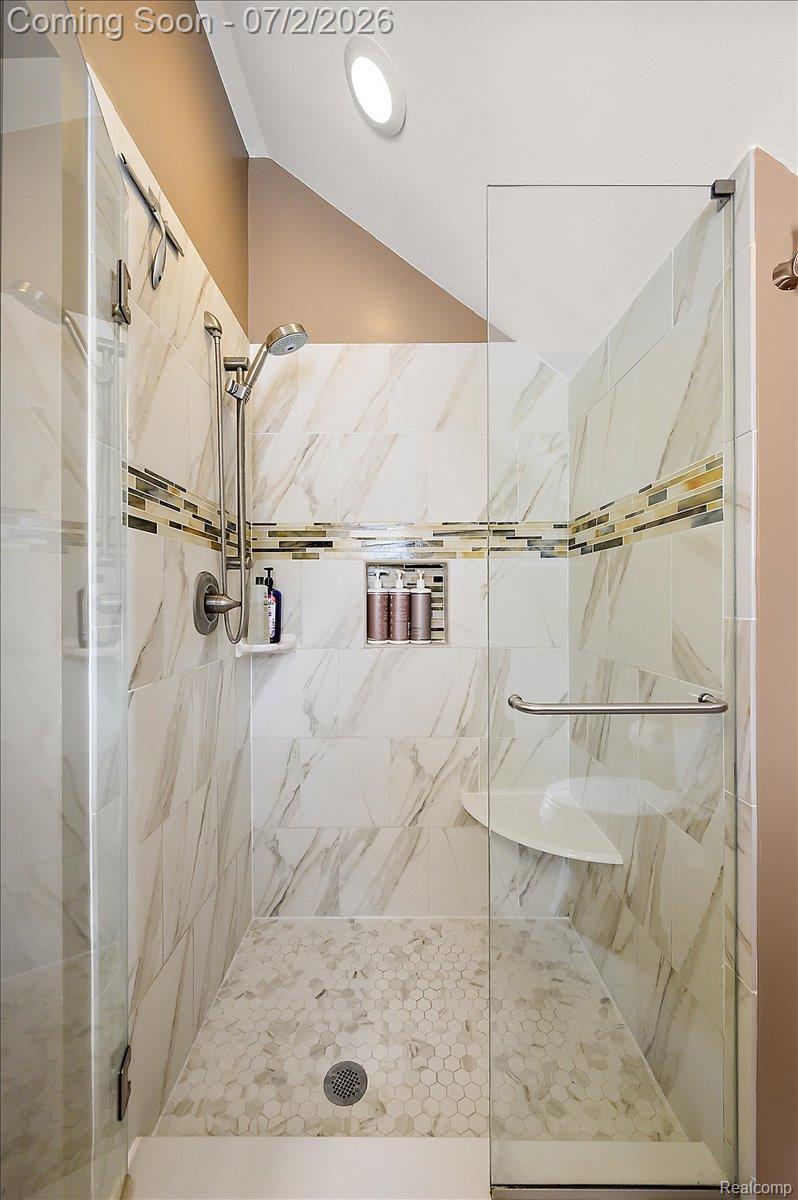 1706 Princeton Road Berkley, MI 48072 - Photo 26 of 49 Shower enclosure featuring floor-to-ceiling marble-look tile, a tiled accent band, and a built-in niche