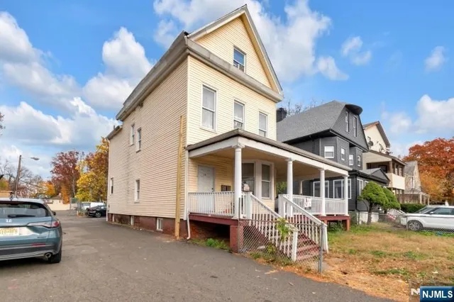 a view of a white house with a large space and a car park in front of it