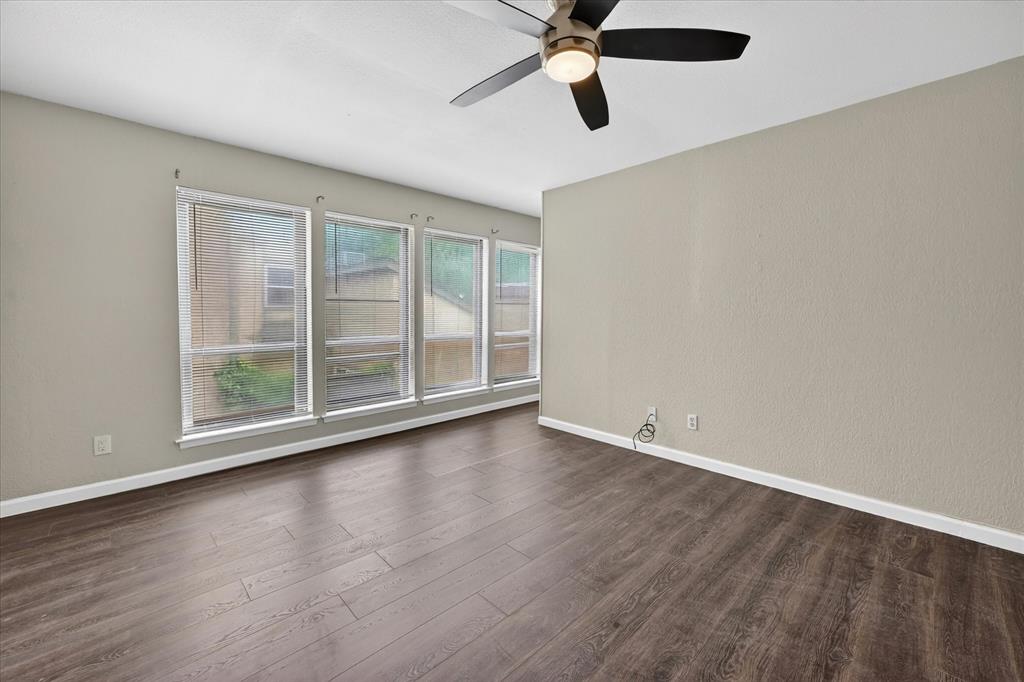 9809 Matchpoint Place Dallas, TX 75243 - Photo 17 of 21 Expansive interior space featuring wood-finish flooring, a wall of four windows with blinds, a ceiling fan with integrated lighting, and neutral-toned walls