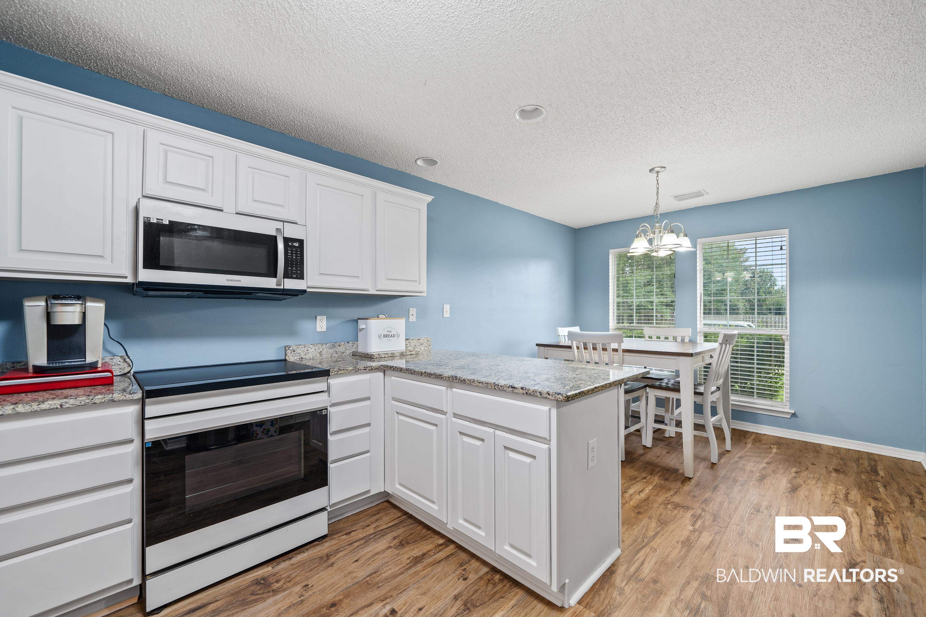 9552 Collier Loop Daphne, AL 36526 - Photo 10 of 28 Kitchen with stainless steel microwave, white range with electric stovetop, light wood finished floors, white cabinets, and a textured ceiling