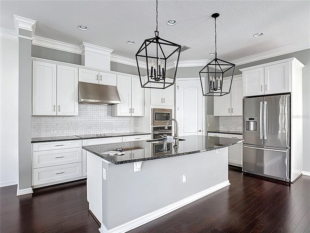 1513 Resolute Street Celebration, FL 34747 - Photo 13 of 43 a kitchen with stainless steel appliances a stove a sink dishwasher a refrigerator and white cabinets with wooden floor