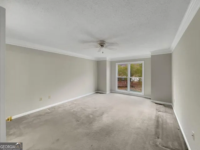 an empty room with a ceiling fan and window