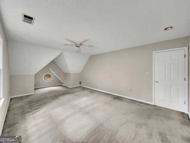 an empty room with chandelier fan and windows