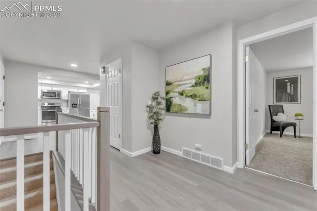 a view of a hallway with wooden floor and a living room