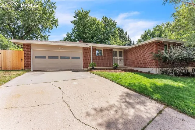 a front view of house with yard and trees in the background
