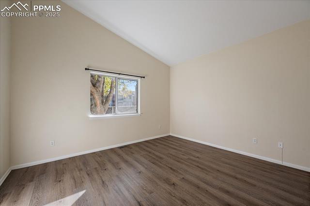 1110 Samuel Point Colorado Springs, CO 80906 - Photo 18 of 28 Unfurnished room with vaulted ceiling and dark wood-type flooring