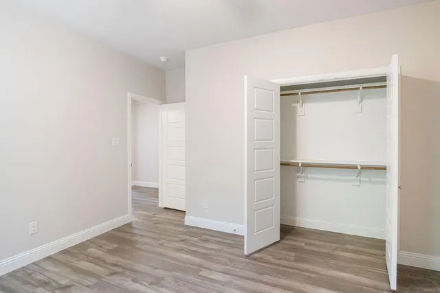 a view of an empty walk in closet with wooden floor
