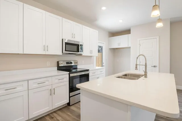 a kitchen with granite countertop white cabinets and stainless steel appliances