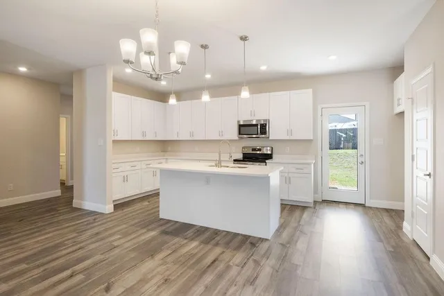 a kitchen with kitchen island white cabinets and stainless steel appliances
