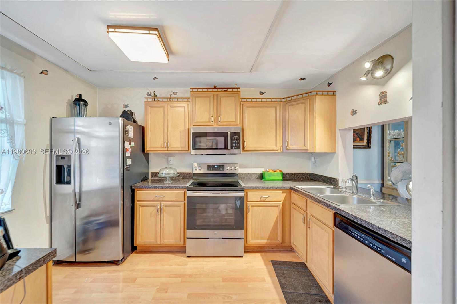 3940 Inverrary Boulevard, Unit 303A Lauderhill, FL 33319 - Photo 2 of 28 a kitchen with stainless steel appliances granite countertop a stove a sink dishwasher a refrigerator white cabinets and wooden floor