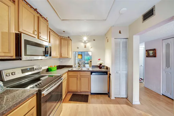 a kitchen with stainless steel appliances granite countertop a refrigerator a stove top oven a sink dishwasher and wooden floor