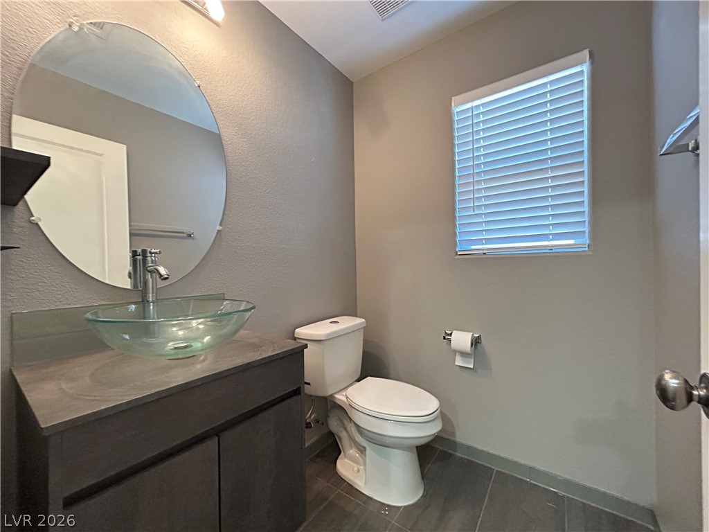 6538 Elm Spring Las Vegas, NV 89148 - Photo 12 of 29 A modern bathroom showcases a unique vessel sink and sleek vanity, offering both style and function.