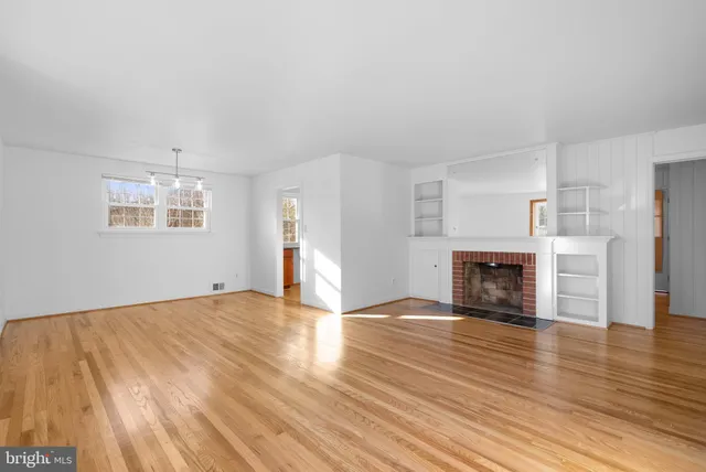a view of empty room with wooden floor and fireplace