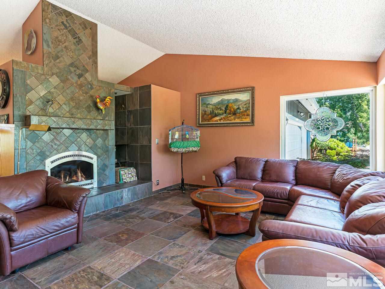 13055 Thomas Creek Road Reno, NV 89511 - Photo 4 of 24 a living room with furniture a fireplace and a floor to ceiling window