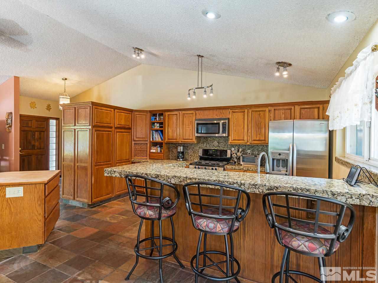 13055 Thomas Creek Road Reno, NV 89511 - Photo 8 of 24 a kitchen with stainless steel appliances granite countertop a table chairs sink and wooden cabinets