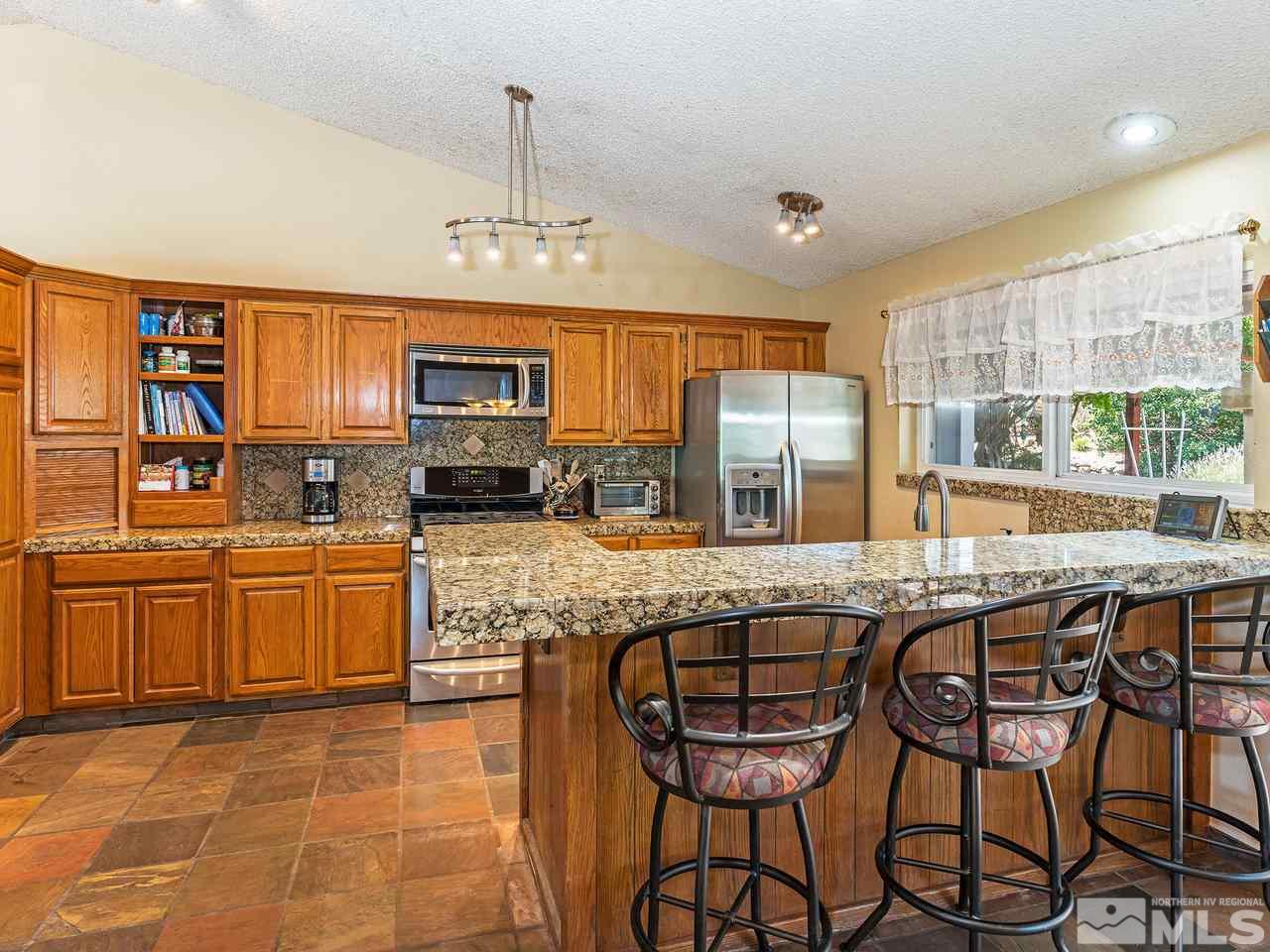 13055 Thomas Creek Road Reno, NV 89511 - Photo 9 of 24 a kitchen with stainless steel appliances granite countertop a stove top oven a sink dishwasher and white cabinets with wooden floor