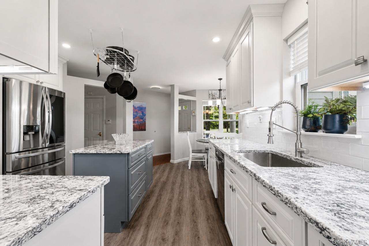 64 Roma Orchard Road Peekskill, NY 10566 - Photo 9 of 40 Spacious kitchen featuring white cabinetry, a large center island with gray cabinetry, stainless steel appliances, and wood-finish flooring