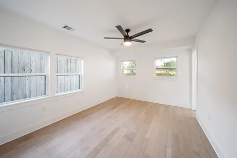 a view of an empty room with a window and wooden floor