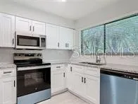 a kitchen with granite countertop a stove sink and microwave