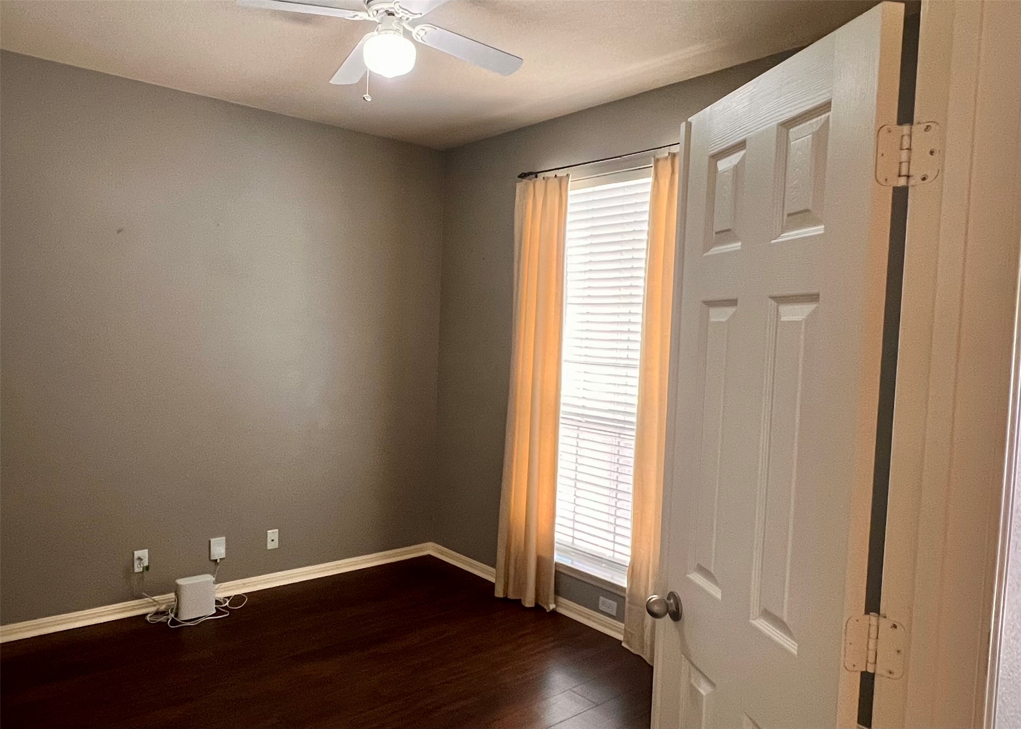 16616 Bridgefarmer Boulevard Pflugerville, TX 78660 - Photo 11 of 36 an empty room with wooden floor and windows with curtains