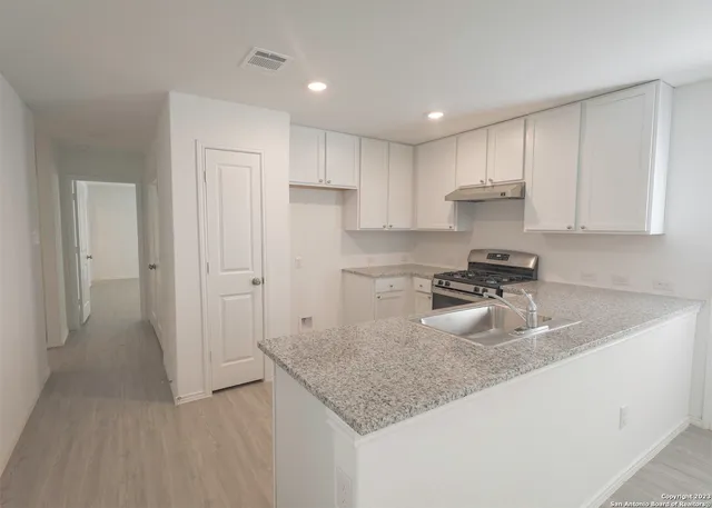 a kitchen with kitchen island granite countertop a sink a stove and refrigerator