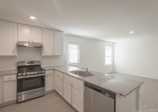 a kitchen with granite countertop stainless steel appliances a sink stove and cabinets