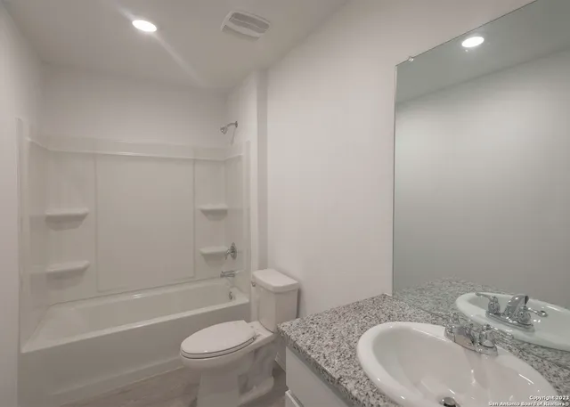 a bathroom with a granite countertop sink a toilet and shower