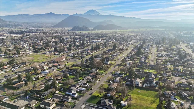 an aerial view of residential house with yard and mountain view in back