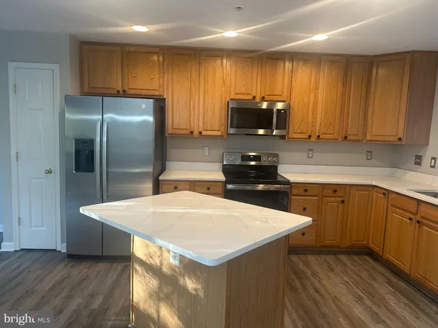 a kitchen with a refrigerator a sink a stove a microwave and wooden cabinets