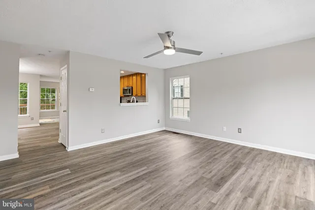 an empty room with wooden floor chandelier and windows