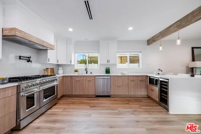 a large kitchen with kitchen island granite countertop a stove a sink a refrigerator and white cabinets with wooden floor