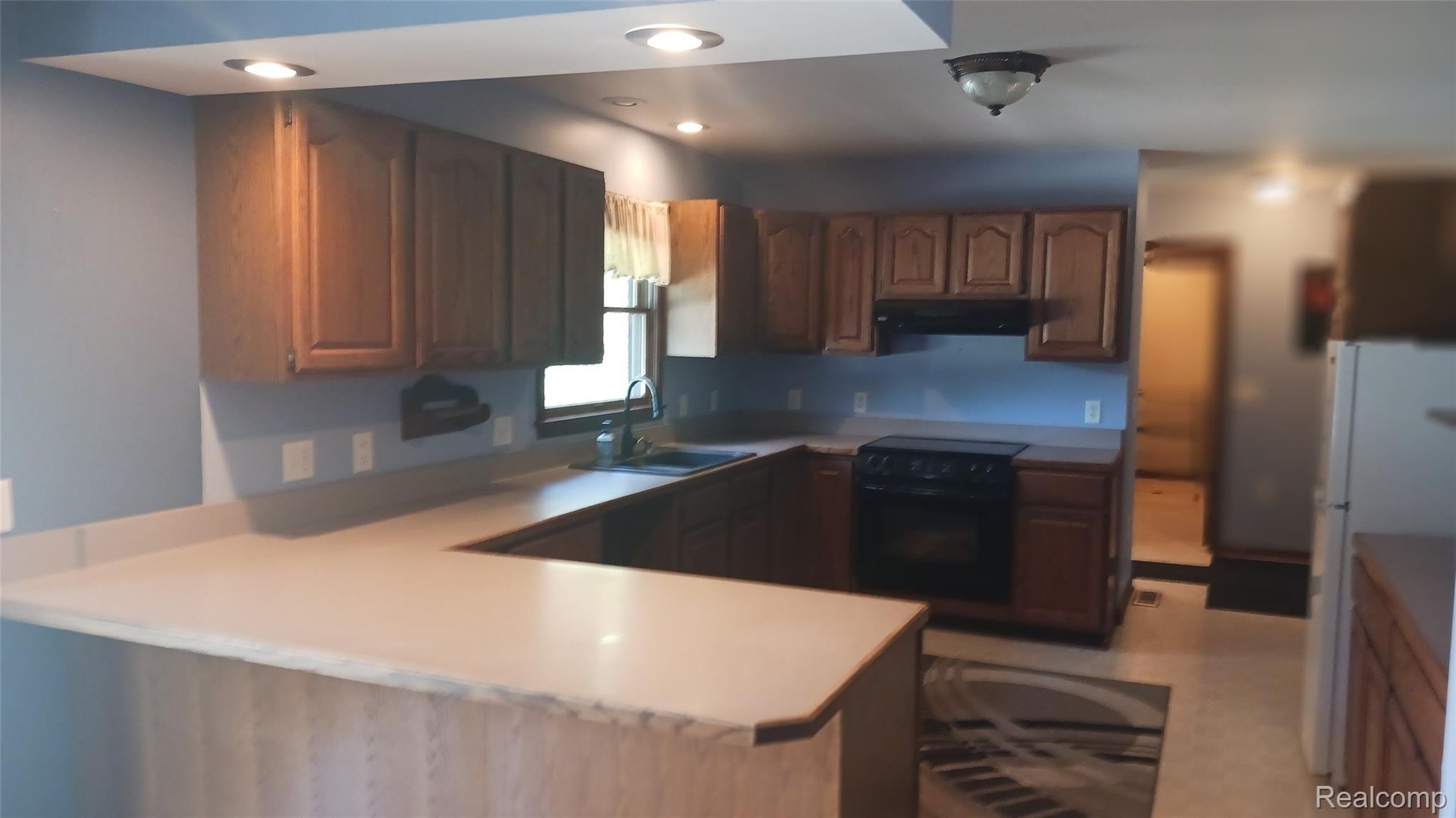 3803 Warner Road Cass City, MI 48726 - Photo 20 of 85 Kitchen with freestanding refrigerator, a peninsula, black range with electric cooktop, light countertops, and brown cabinets